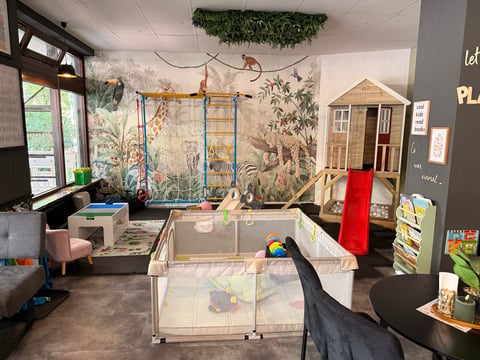 Bright daycare or playroom with colorful wall murals, play structures, toys, and natural light from windows