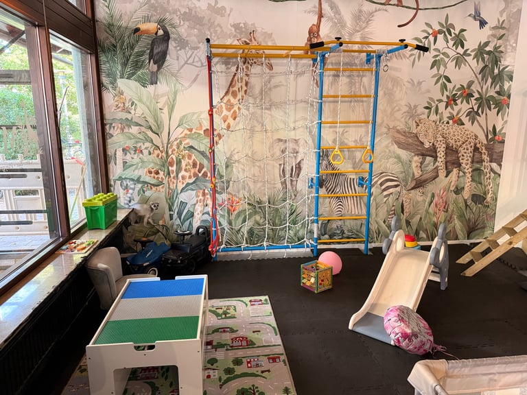 Childs bedroom with wall mural of jungle animals, play gym, toys, and sliding board near window